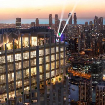 Dubai városi táj, felhőkarcolók és világító épületek a naplementében.