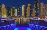 Dubai Marina éjszakai városképe, magas épületekkel és vízparti látvánnyal.