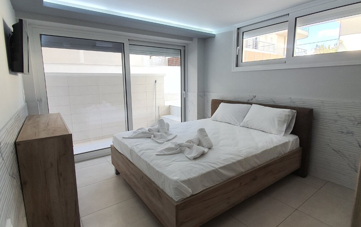 Hálószoba világos bútorokkal, friss ágyneművel és nagy ablakokkal.