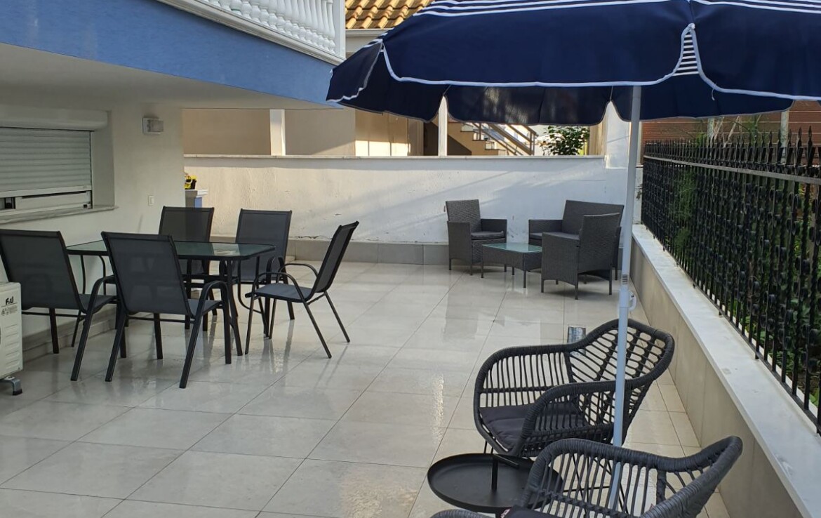 Terasz területén elhelyezett székek, asztal és napernyő látható.