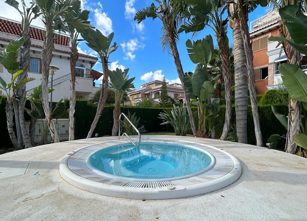 Kerek jakuzzi medence, amely körül növények és pálmafák találhatók.