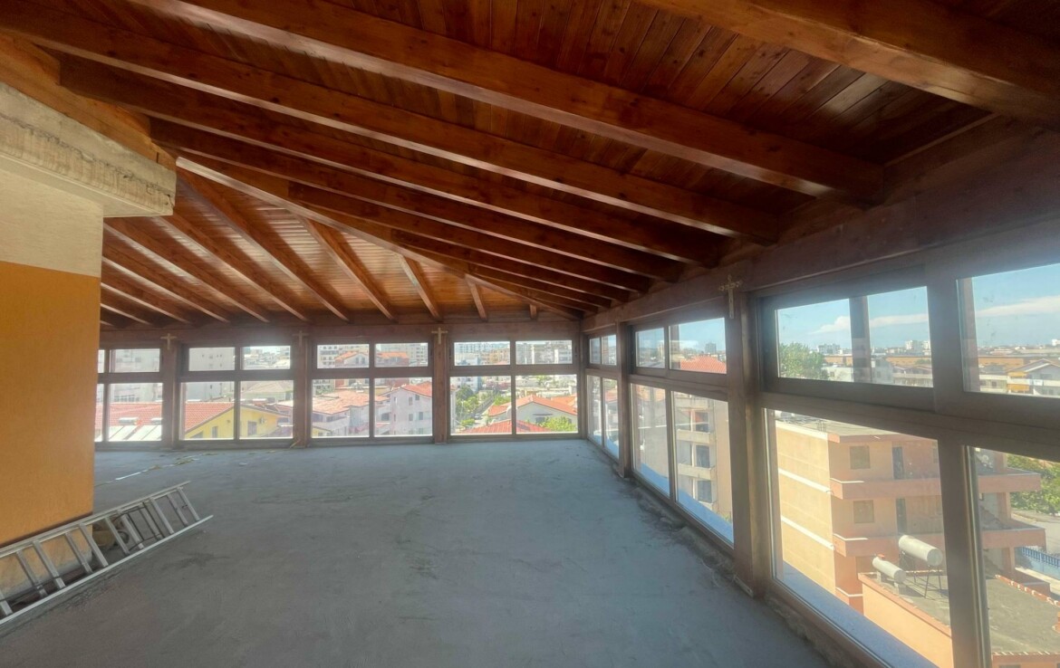Tetőtéri ingatlan belső nézet, nagy ablakokkal és fából készült mennyezettel.